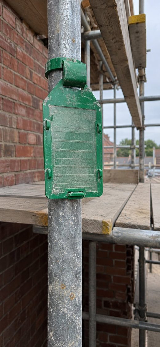 Stamped photo of a green scaffold inspection tag fixed to a scaffold tube, in the PicAnchor camera